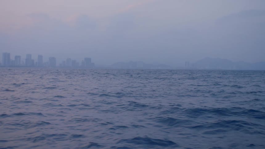 Waves in the ocean with a city skyline in the distance