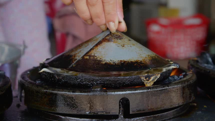 A woman cooks bean sprouts on an old fashioned pan