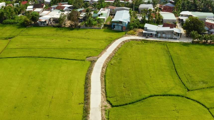 Aerial view of motorcycle driving on a street next to grass field and entering a neighborhood