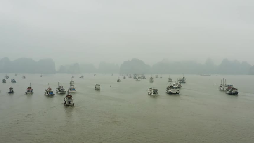 Boats sailing towards land in heavy fog