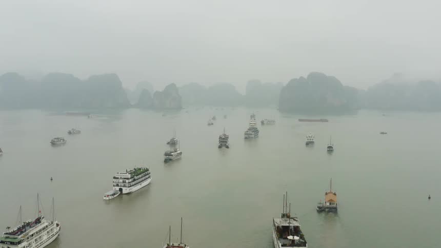 Boats floating in a harbor on a misty day