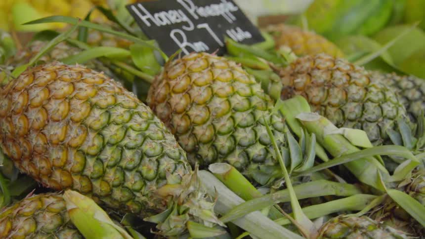 A stack of pineapples on a fruit stand at market