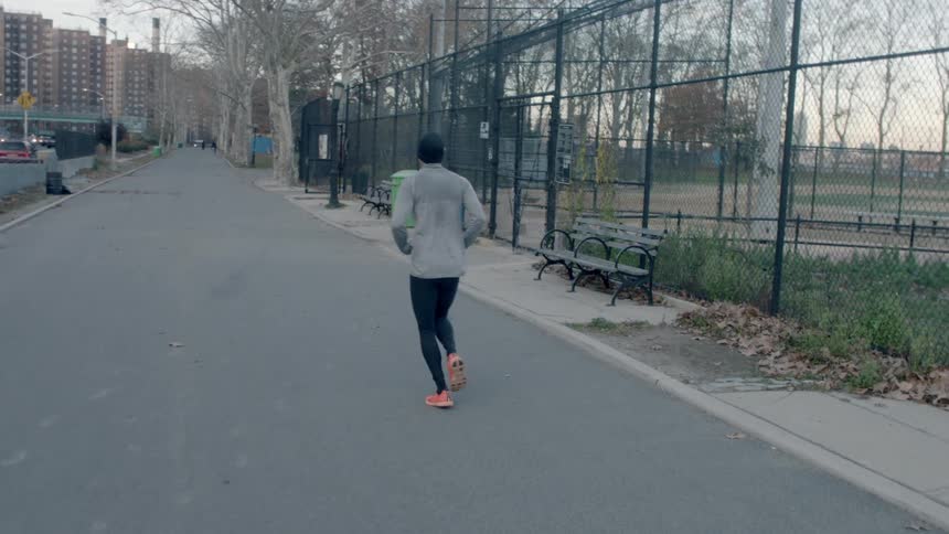 A person is running outside near a fence