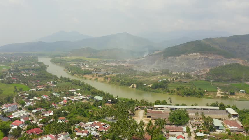 An aerial view of a neighborhood with a river behind it and hills in the distance