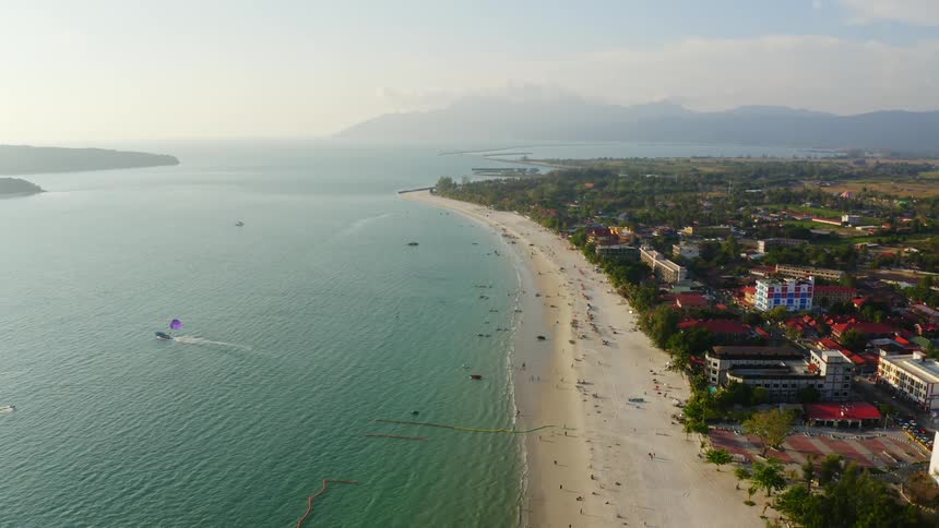 People enjoying the beach of a small coastal town near the mountains