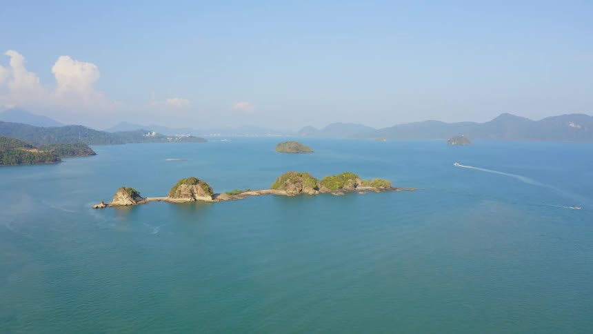 An ocean with islands surrounded by water with the sky and clouds in the background