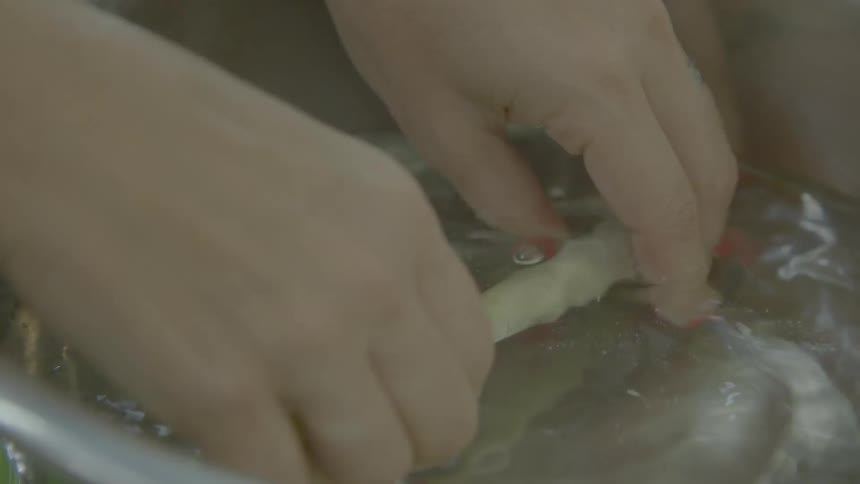 A person washes food in a bowl of water
