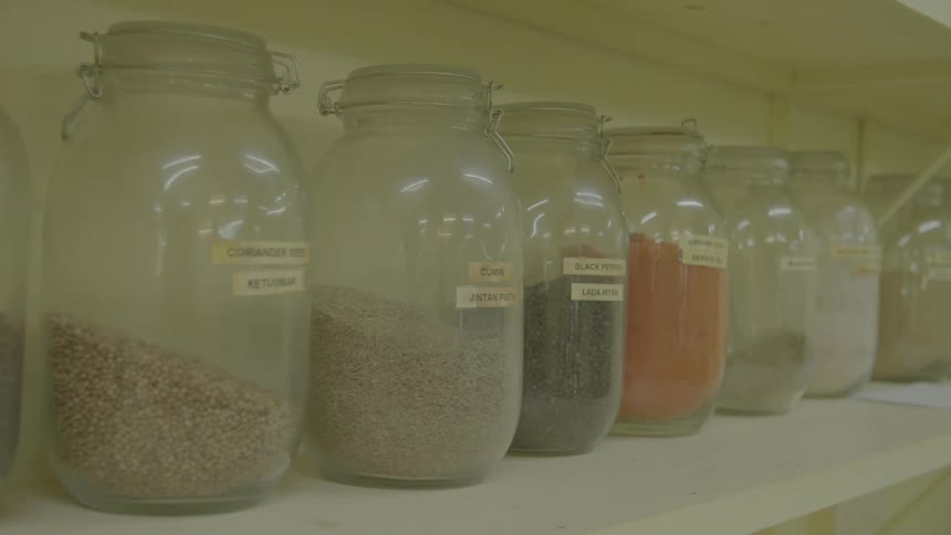 Glass jars of spices and seasonings lined up on a shelf