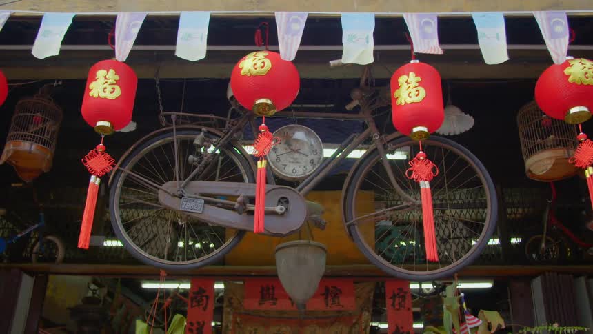 A bicycle hangs behind some chinese lanterns on the front of a shop