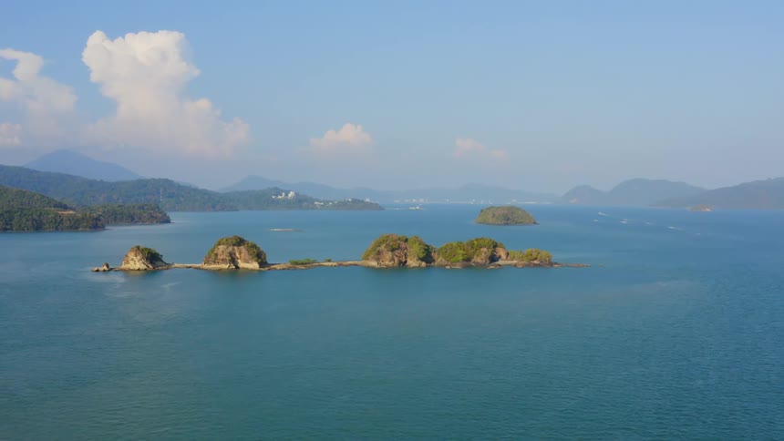 An ocean with islands surrounded by water with the sky and clouds in the background