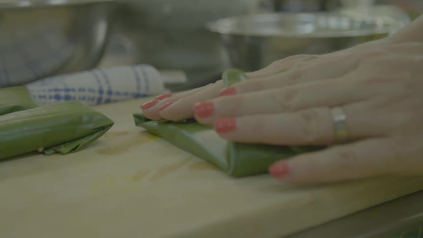 A woman preparing food on a cutting board in a kitchen