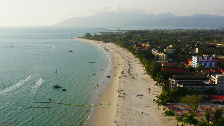 An aerial view of hotels and people on a beach and boats in the water