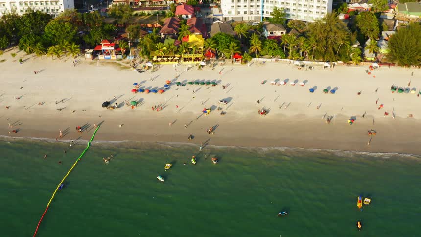 A beach filled with beach goers near a city