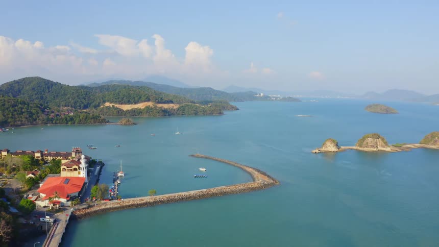Forest covered mountains and colorful roofed resort border ocean