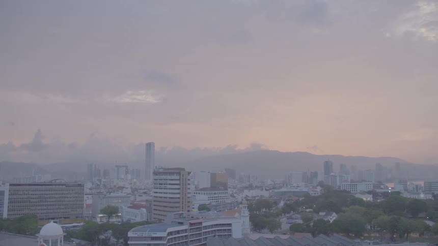 Fog sets over a dense city with a mountain range in the horizon