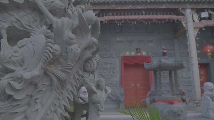 A building in an asian country is adorned with a red door and numerous sculptures