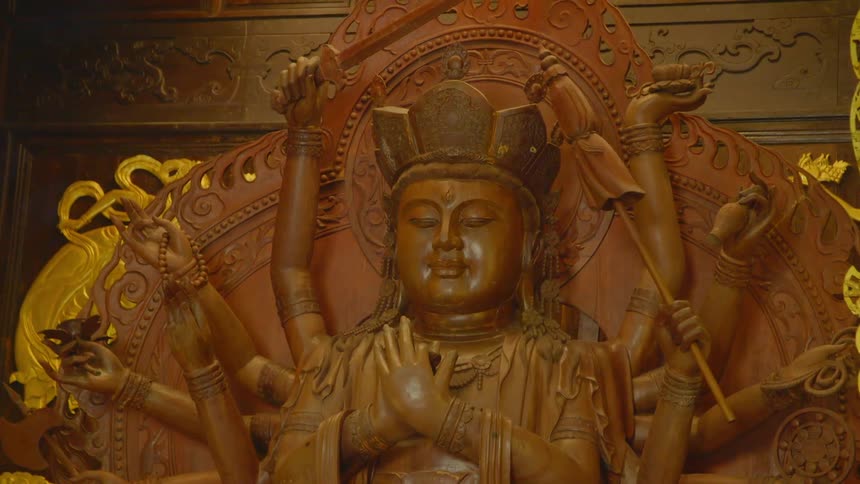 A carving of a wooden statue with a wall in the background