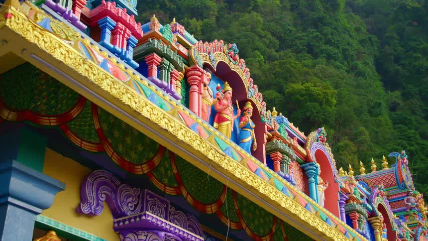 A color asian shrine includes carvings of religious figures along the roof