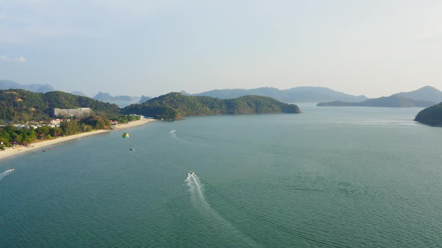 Boats travel across the ocean off the coast of a small town