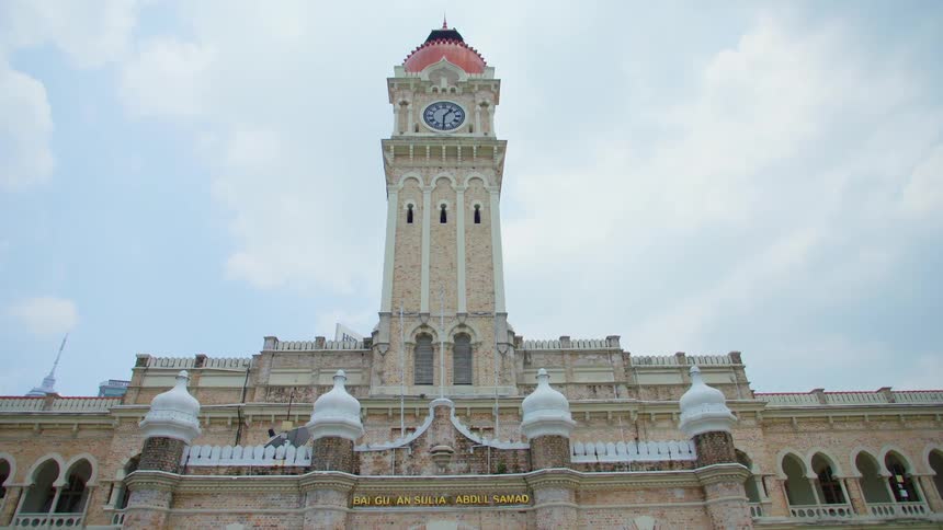 A large building with a tall clock tower on the top under a bright daytime sky