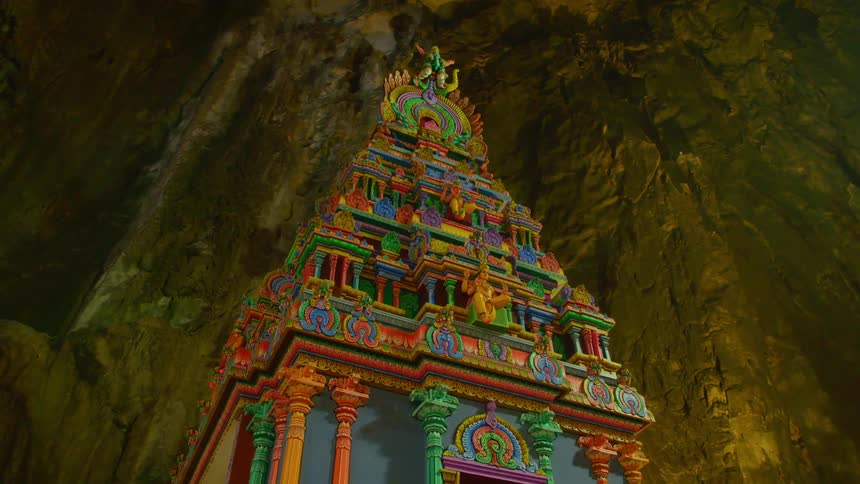 A colorful tower lies near a large stone wall