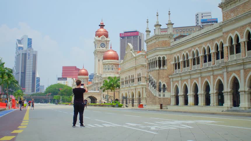 People in front of a large temple take pictures and walk past as they look