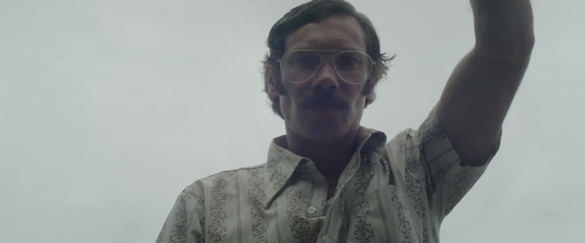 Man wearing glasses and mustache closes the trunk of a car