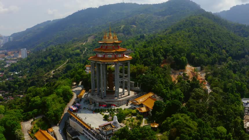 A monument surrounded by trees with buildings hills the sky and clouds in the background