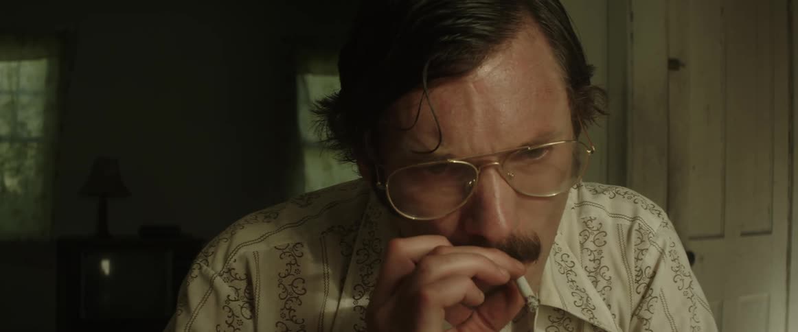 A male on a telephone smoking in a house