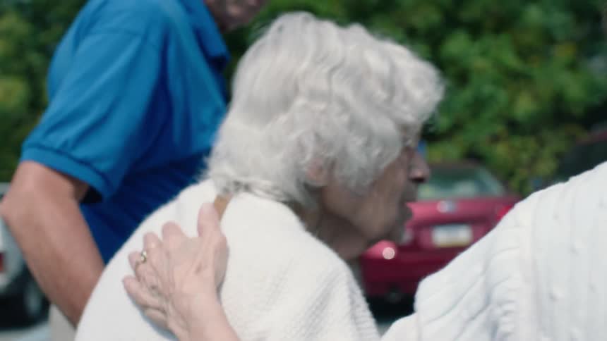 Older people helping an even older person walk outside