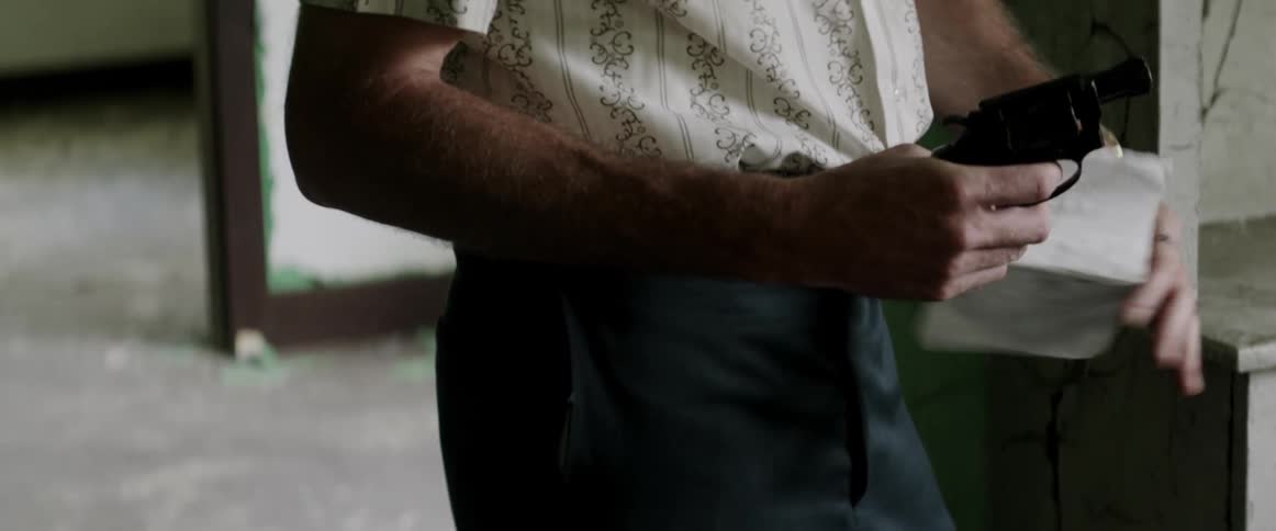 A man holding a gun takes a piece of paper from another man