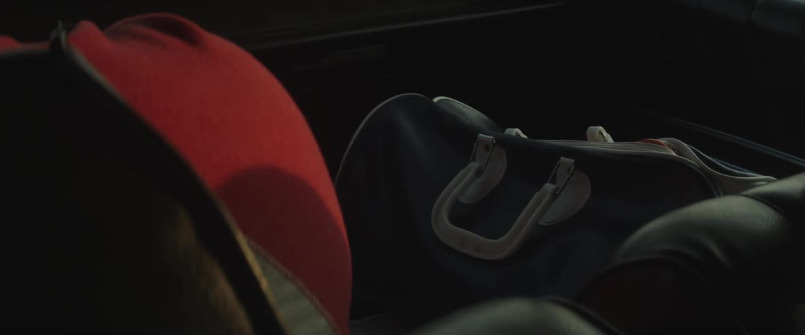 A woman reaches into her backseat and touches her luggage as the car is moving