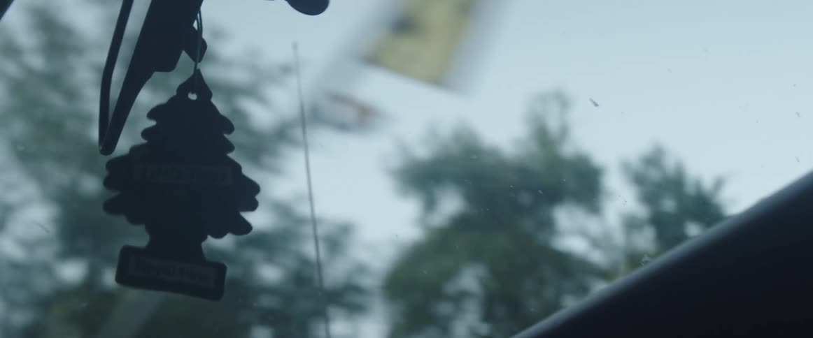 An air freshener hanging from a rearview mirror in a moving car