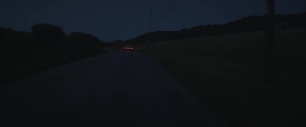 A car driving down a dark road at night