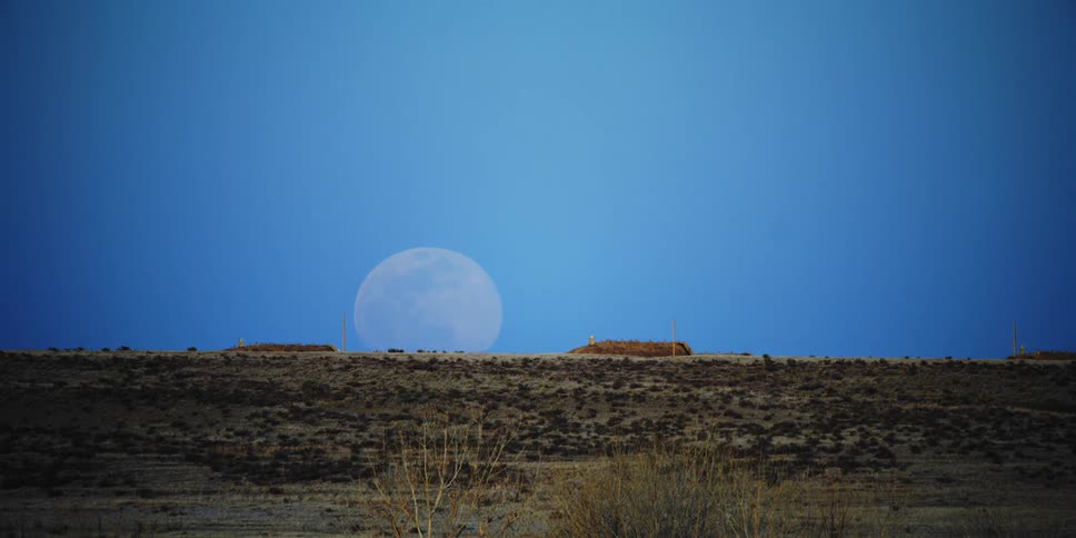 The moon rising over a hill in the desert