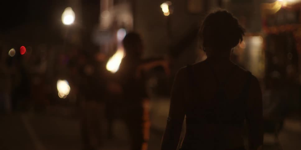 A woman watches fire dancers performing on the street at night