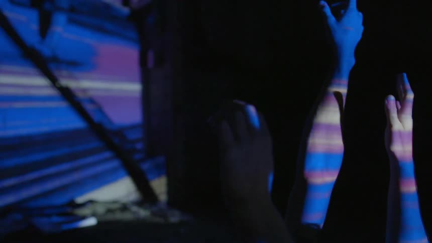 Hands raised in the air in front of bright blue lights at a nightclub