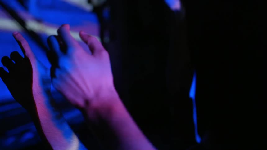 People hold their hands up under flashing lights