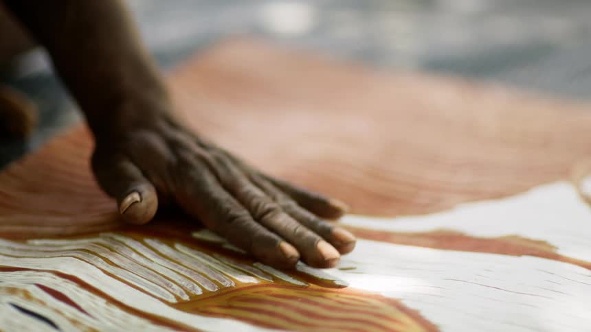 A person brushing off a painting they are working on
