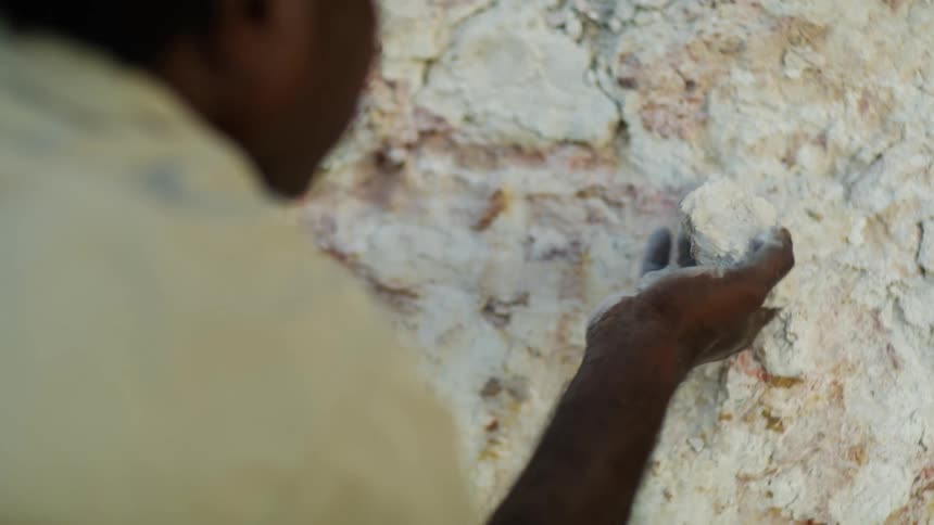 A man is crumbling a piece of stone