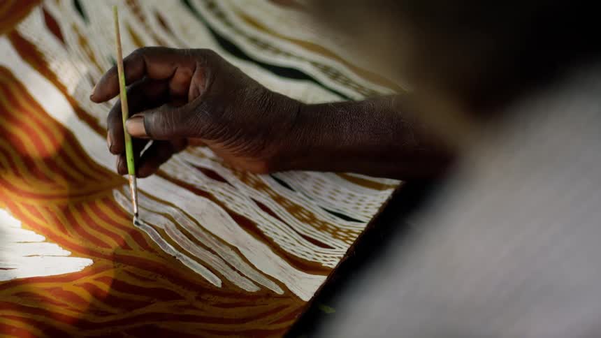A man is painting on a canvas