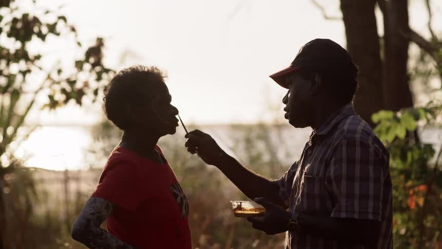 A man paints tribal paint on a womans face