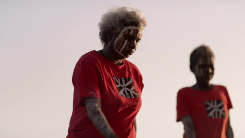Two women dancing outdoors with face paint on
