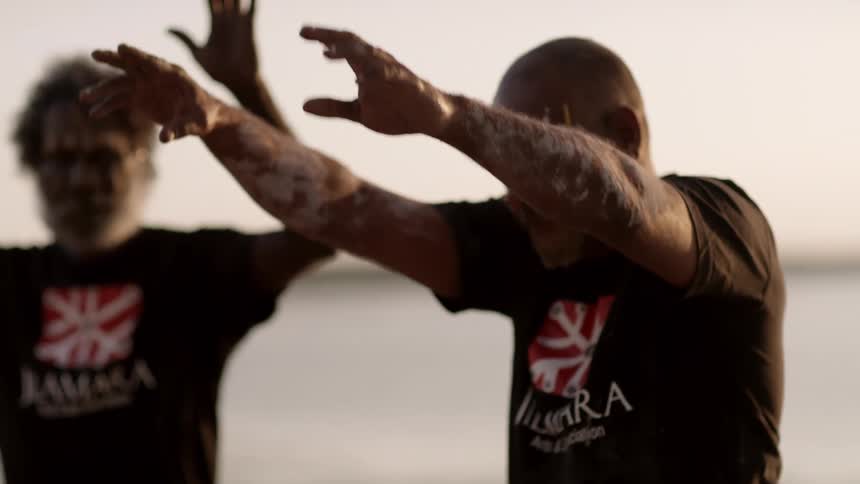 People clapping and performing a tribal dance on a beach