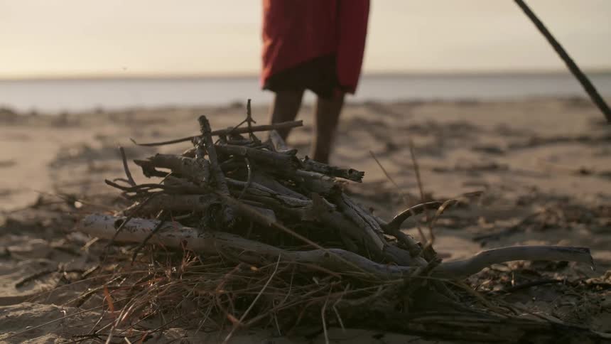 A woman builds a fire pit on the beach