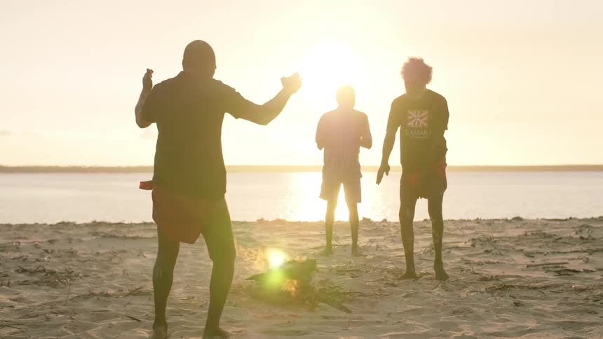 Ritual dance of indigenous people around a fire on the beach at dusk