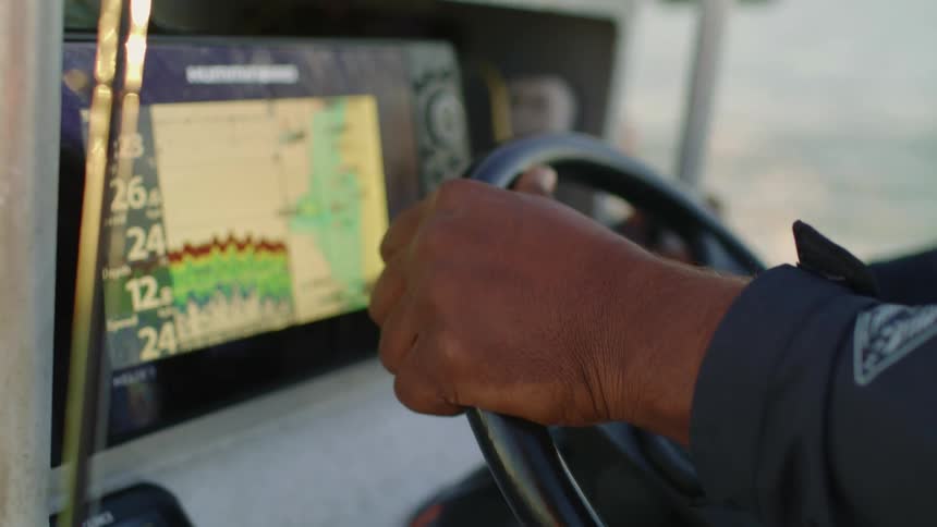 A man uses a navigation system as he steers a boat in the ocean