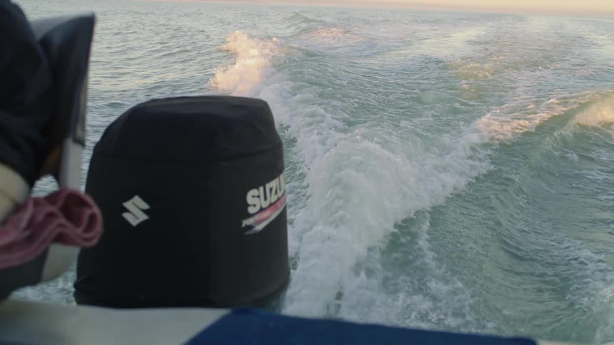 A boat leaves a trail of waves behind it as it sails through the ocean
