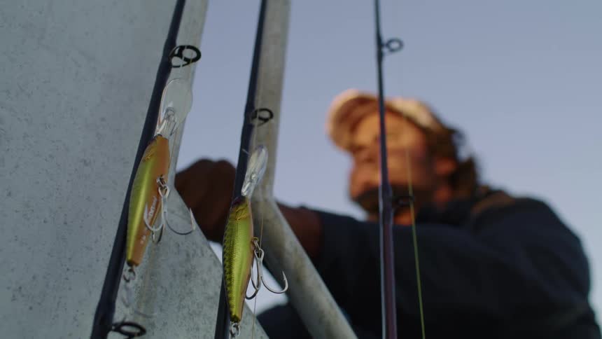 Fishing rods with hooks and lures with a man with a hat in the background