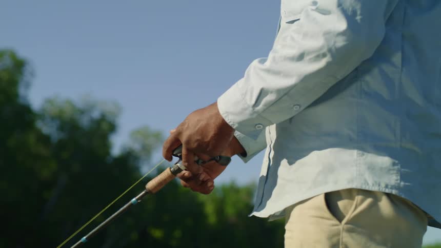Man with a cap a beard and a blue shirt casts a fishing line